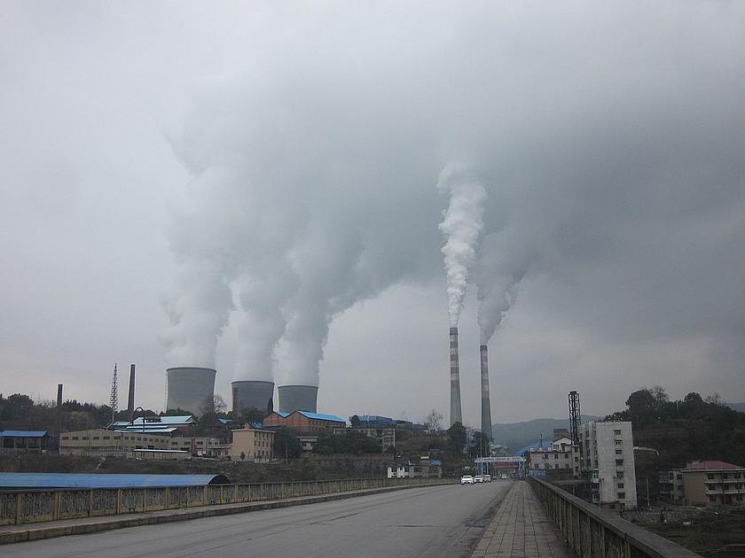 Ein Kohlekraftwerk in China an einer Straße. Der Himmel ist grau.