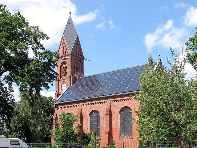 dunkle Solarmodule auf einer Backsteinkirche