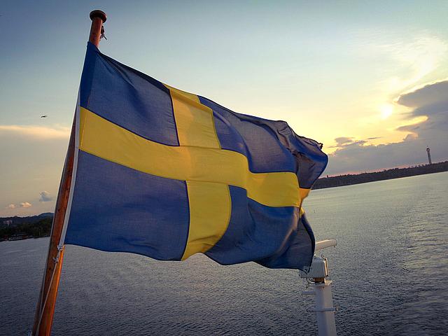 Schwedische Flagge an einem Schiff mit Sonnenuntergang im Hintergrund