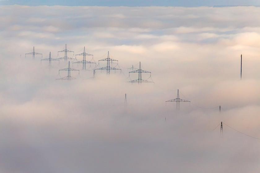Spitzen von Strommasten ragen aus Nebel