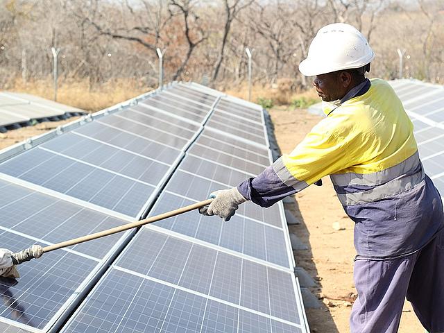 Ein Arbeiter in Tansania reinigt Solarpanels