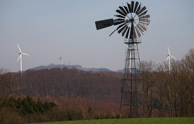 KLeines Windrad, im HIntergrund große Windenergieanlagen