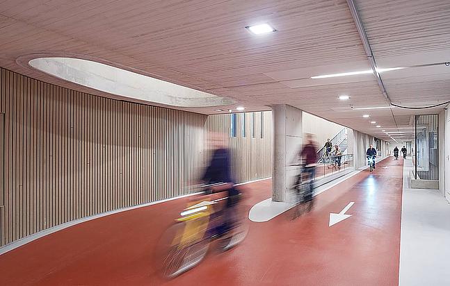 Bild aus dem inneren eines Gebäudes mit Fahrradspuren, auf denen Fahrradfahrer fahren.