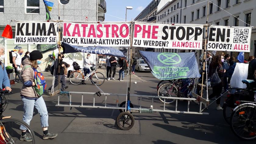 Banner mit der Aufschrift: "Klimakatastrophe stoppen! Was hindert Sie noch Klimaaktivist:in zu werden? Handelt! Sofort! Alle!