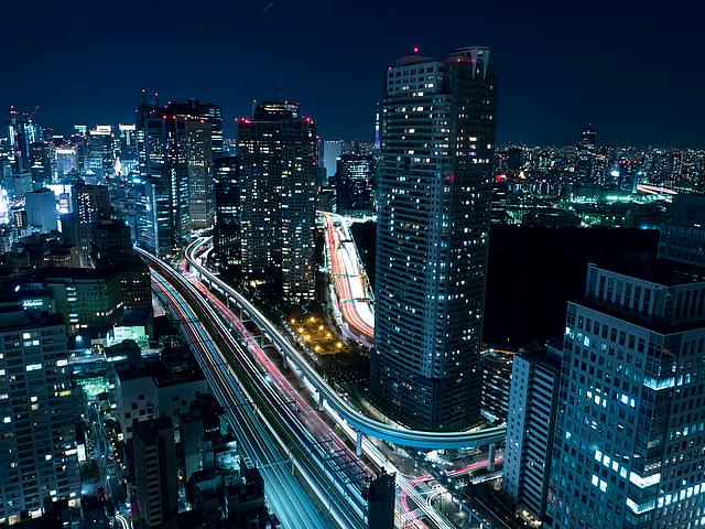 Das World Trade Center Tokyos bei Nacht. Dunkle Wolkenkratzer. Unten ziehen sich glitzernd Straßen entlang