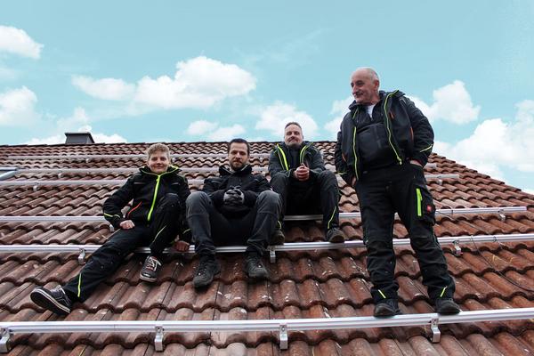 Vier PV-Installateure auf Hausdach
