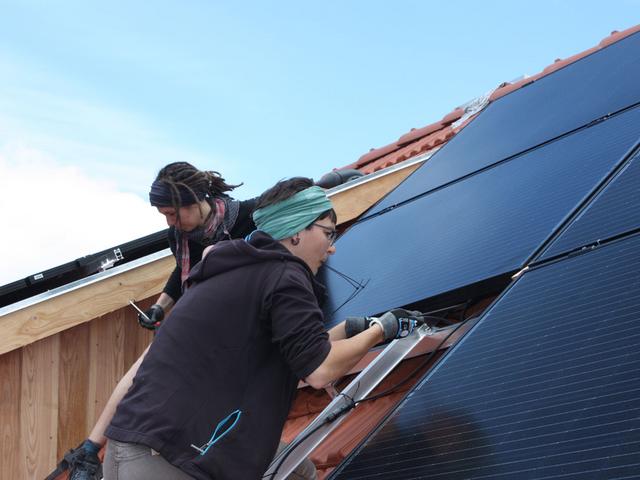 Zwei Installateurinnen arbeiten an PV-Anlage auf dem Dach