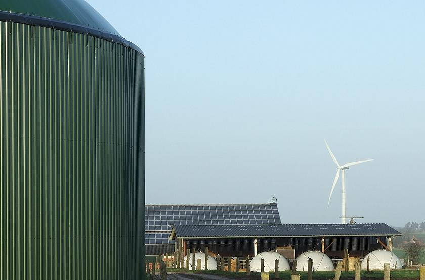 Biogasanlage, im Hintergrund Gebäude mit Photovoltaik und ein Windrad