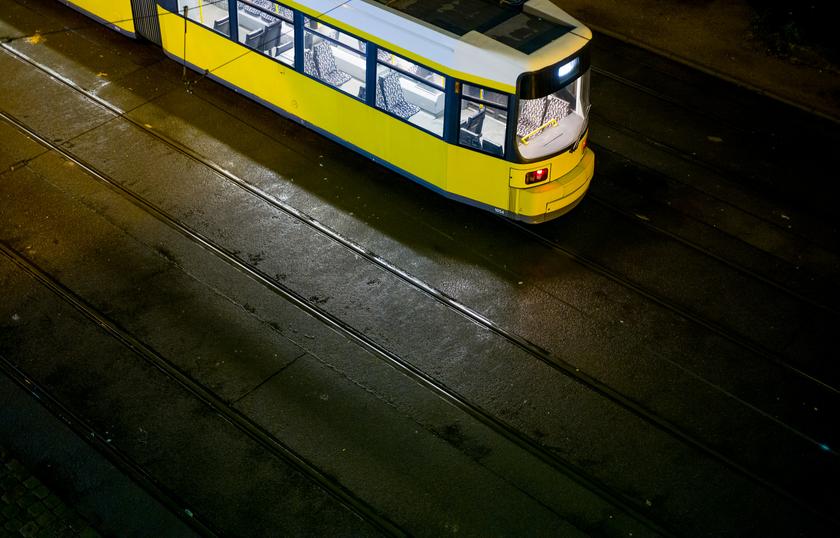 Eine gelbe Straßenbahn am Abend auf Schienen.