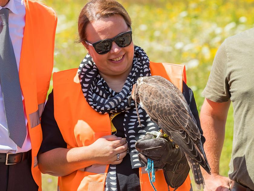 Umweltministerin NRWs Ursula Heinen-Esser mit Sonnenbrille und einem Greifvogel auf dem Arm