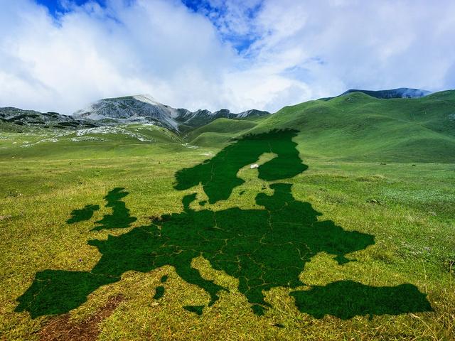Schatten in Form einer Europa-Karte auf einer grasbewachsenen Hügellandschaft