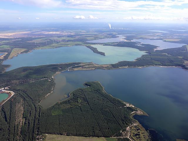 Luftaufnahme einer Landschaft mit Seen und Tagebauen und Kohlekraftwerken im Hintergrund
