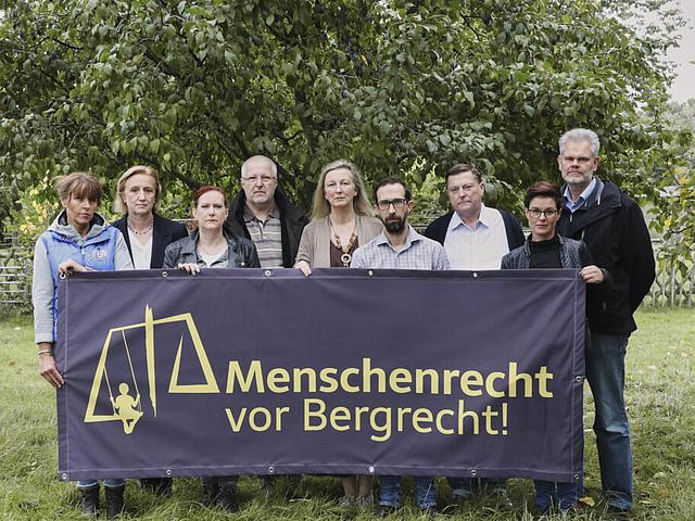 Eine Gruppe von Personen hinter einem Banner, auf dem steht Menschenrecht vor Bergrecht.