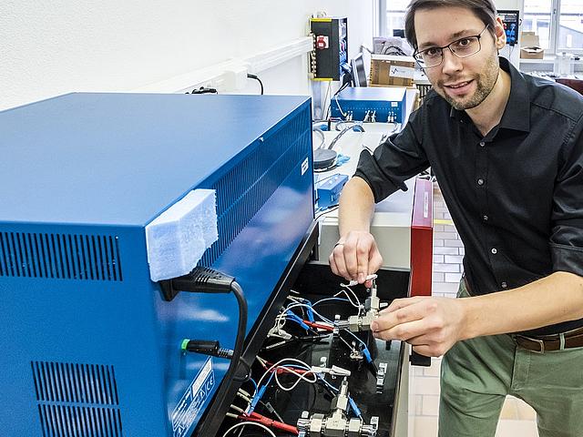 Empa-Forscher Ruben-Simon Kühnel schließt eine Test-Batteriezelle mit der konzentrierten Salzlösung an ein Ladegerät an. (Foto: © Empa)