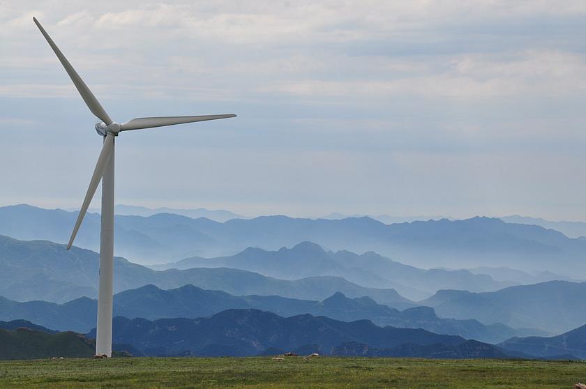 Eine einzelne Windnergieanlage vor einem Bergpanorama.