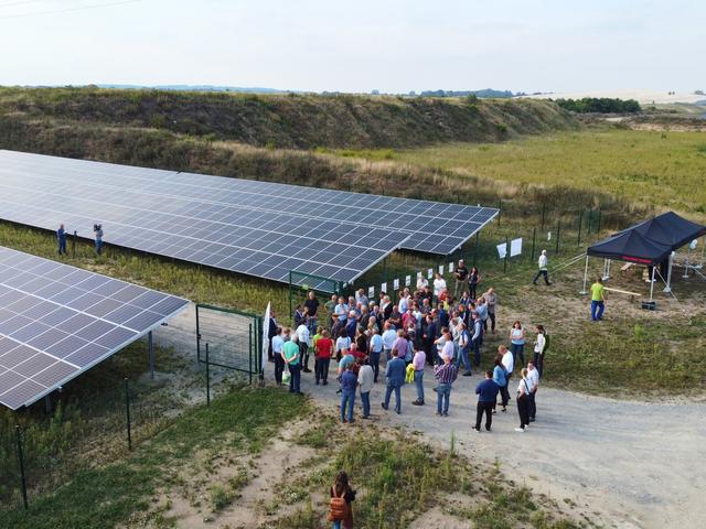 Luftbild eines Solarparks mit Menschen davor.