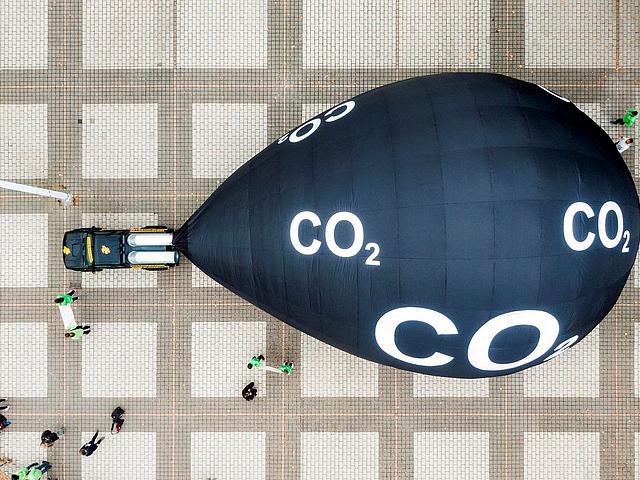 Luftbild des Platzes vor dem Eingang zur IAA. Dort sind Menschen um ein Auto, mit einem riesigen schwarzen Ballon hintendran zu sehen.