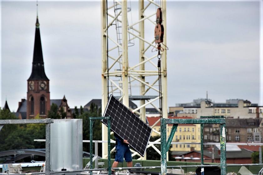 Mann mit Photovoltaikmodul auf einem Berliner Dach.