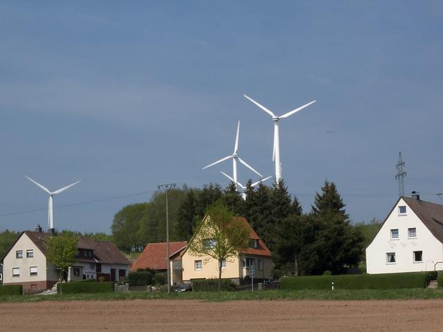 Häuser, im Hintergrund Windenergieanlagen