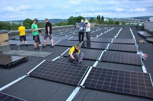 Menschen arbeiten auf einem Flachdach an einer Solaranlage