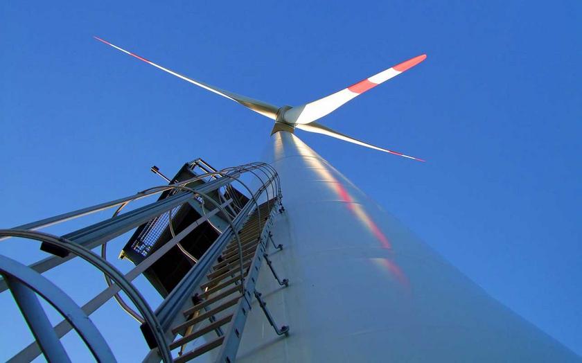 Windkraftanlage von unten mit Leiter und blauem Himmel