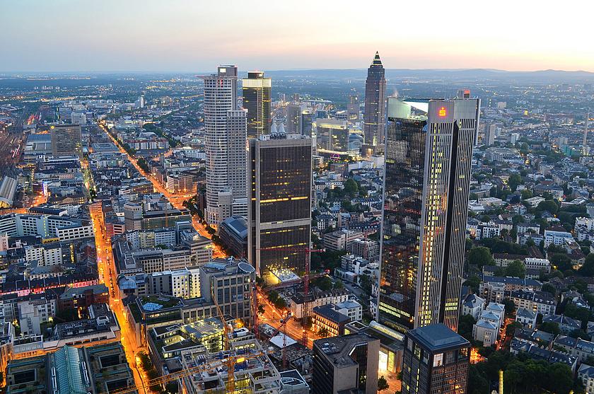 Blick auf die Skyline Frankfurts am Abend. Hochhäuser und beleuchtete Straßen.