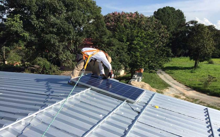 Mann mit Strohhut legt Solarmodul auf Pfalzdach