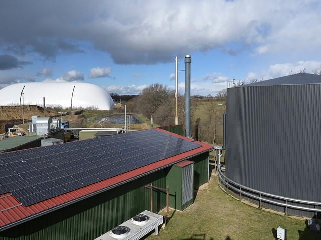Stall mit Solarmodulen und eine Biogasanlage mit Speicher