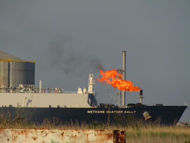 EIn Schiff vor einem LNG-Terminal, wo Gas abgefackelt wird