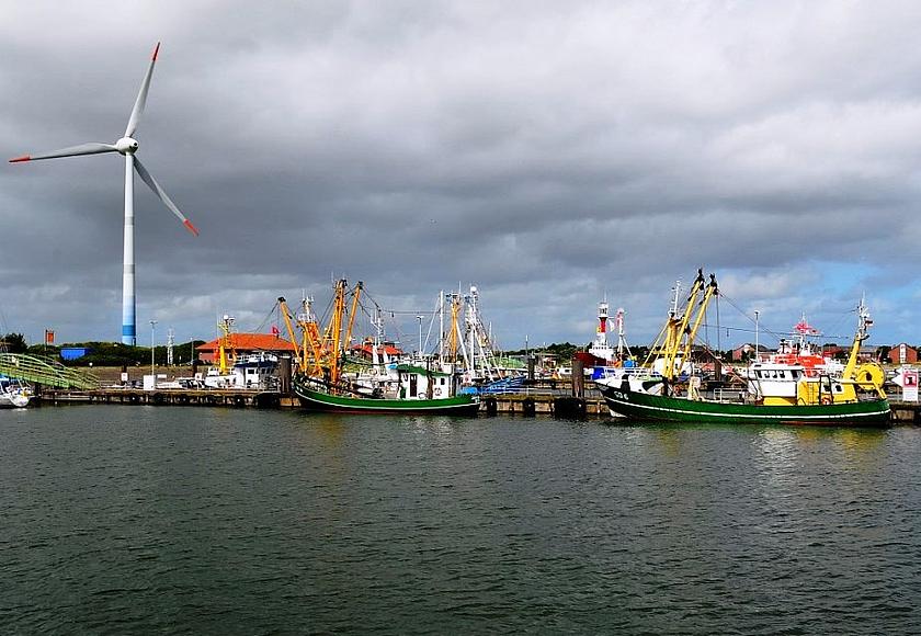 Kleiner Nordsee-Hafen mit Fischerbooten und einem Windrad