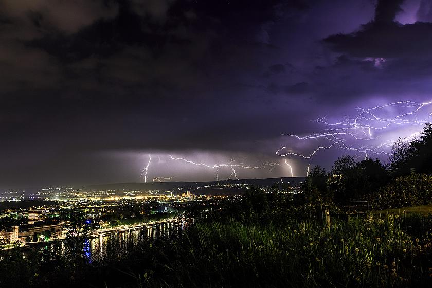 Foto: Bild eines herannahenden Gewitters mit Blitzen, in der Nähe einer Stadt.