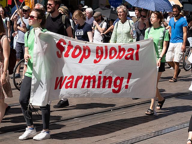 Demonstranten tragen ein Banner „Stop Global Warming“