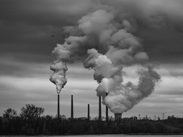 Schwarzweiß-Bild einer Industrieanlage mit vielen Emissionen