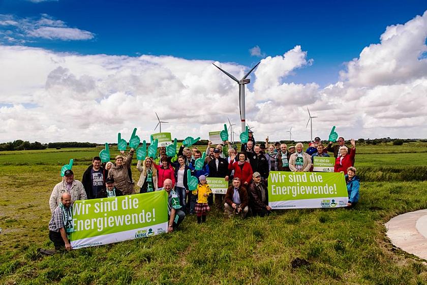Menschen einer Energiegenossenschaft vor Windrädern