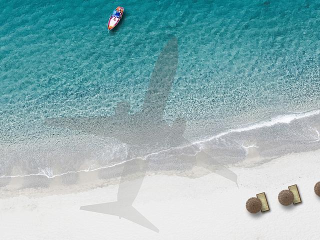 Schatten eines Flugzeuges auf einen idyllischen Sandstrand und das Meer