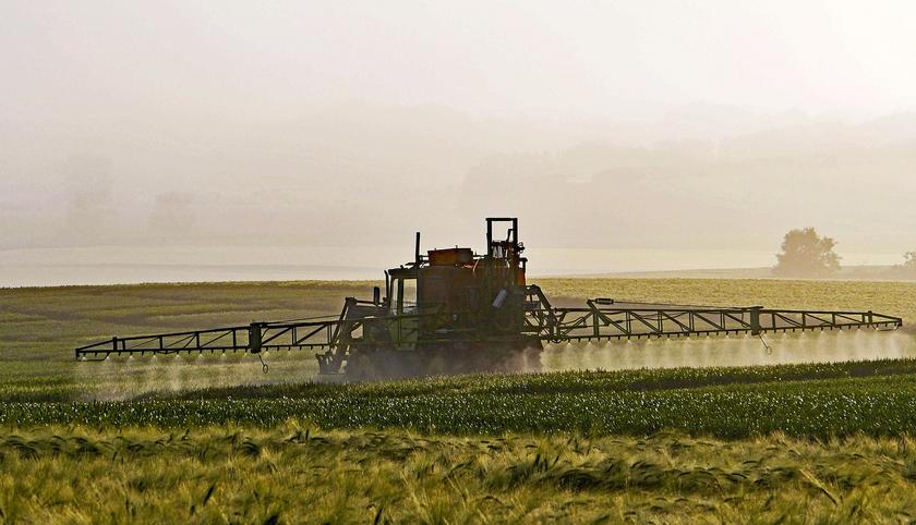 Traktor bringt Pestizide auf Acker aus