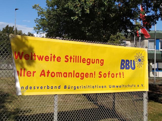 Plakat an einem Zaun, Protestaktion des BBU: Weltweite Stilllegung aller Atomanlagen – sofort. BBU