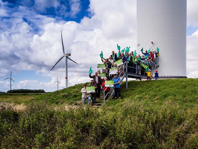 Bürgerenergiegemeinschaft versammelt sich vor ihrem Windrad