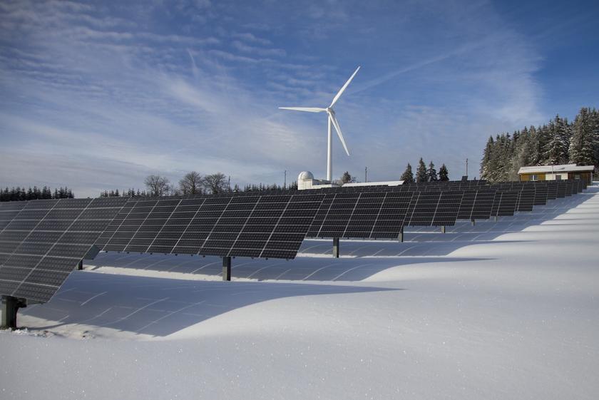 Solarpark und Windkraftanlagen in Schnee-Landschaft