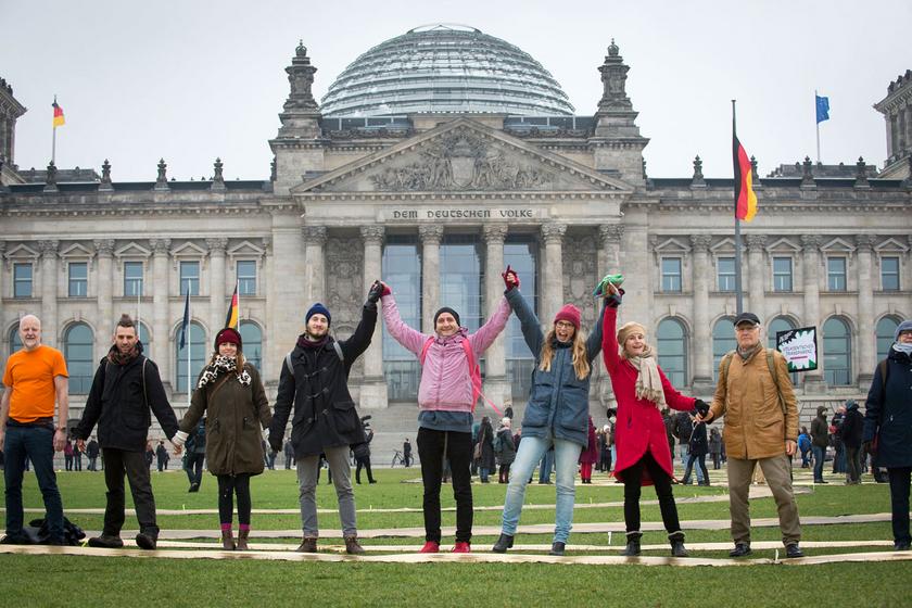 Menschenkette mit fröhlichen Gesichtern vor dem Reichstag in Berlin