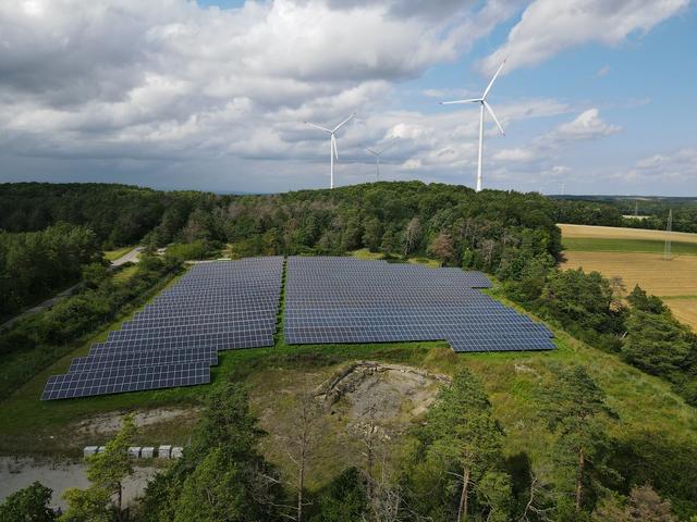 Solarpark und Windenergie-Anlagen, dazwischen Wald