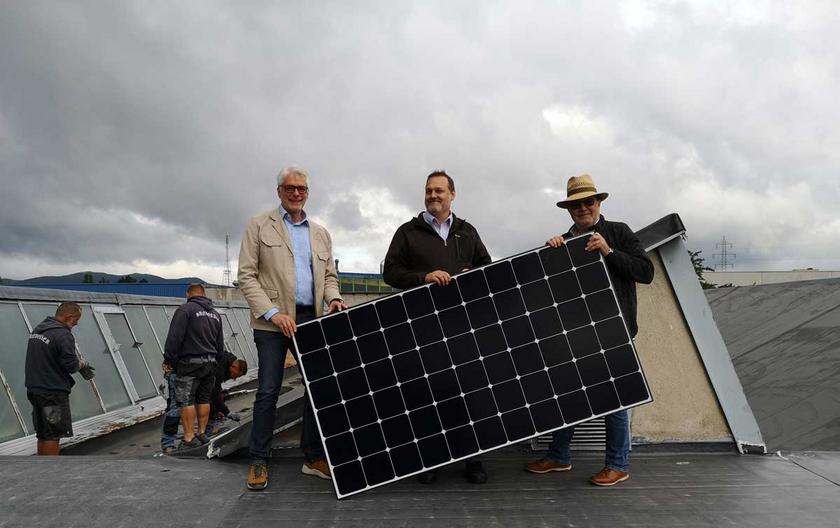 drei Männer mit Solarmodul auf einem Dach