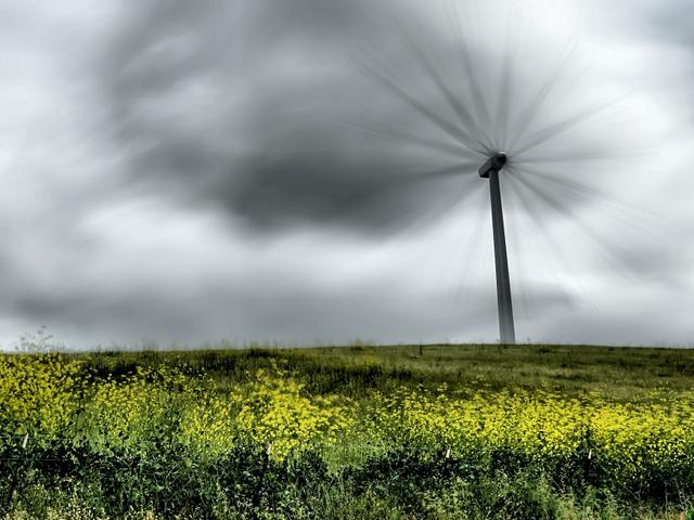  Windkraftanlage mit schnell rotierenden Flügeln in einem Rapsfeld