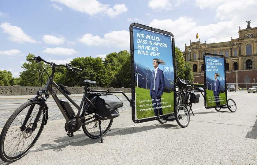 Fahrrad mit Plakatwand auf Anhänger, abgebildet Markus Söder und Text: Wir wollen dass in Bayern ein neuer Wind weht