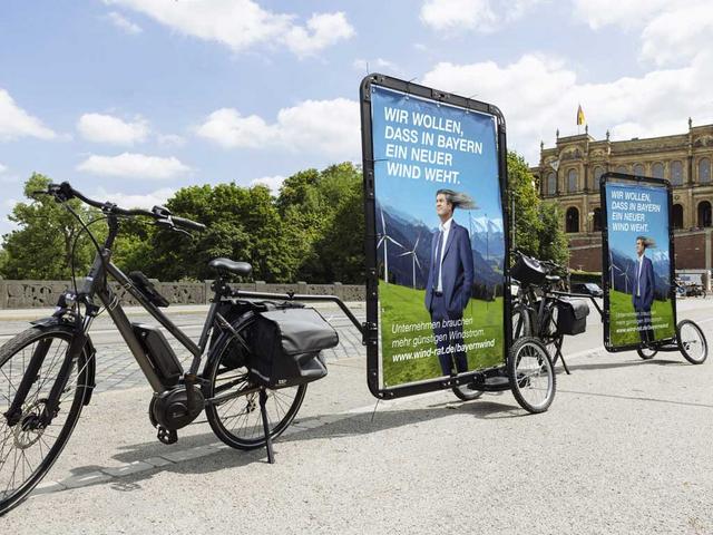 Fahrrad mit Plakatwand auf Anhänger, abgebildet Markus Söder und Text: Wir wollen dass in Bayern ein neuer Wind weht