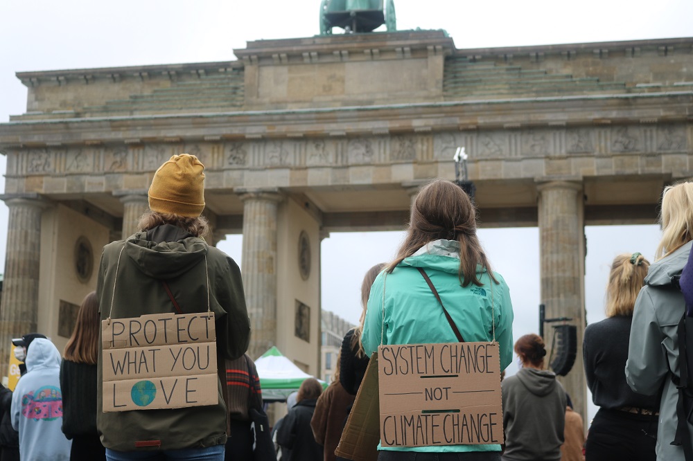 Zwei Klimaaktivistinnen mit Schildern vor dem Brandenburger Tor