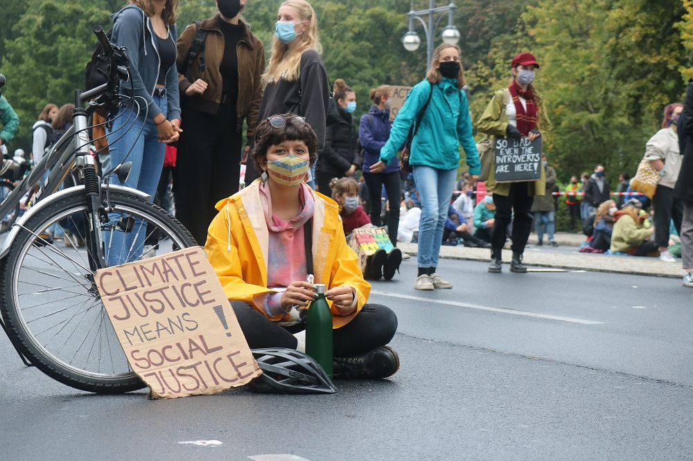 Eine Klimaaktivistin sitzt auf der Straße mit einem Schild