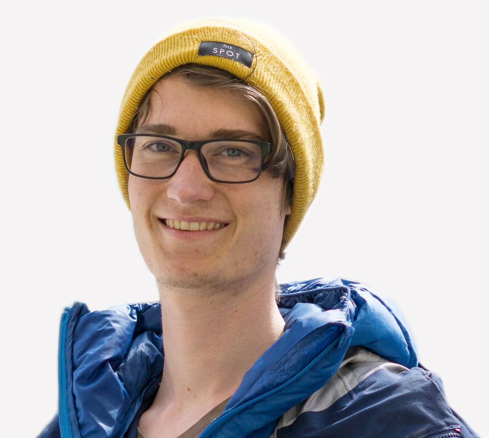 Mark Schöne - ein Mann mit blauer Jacke, Brille und gelber Mütze im Profil