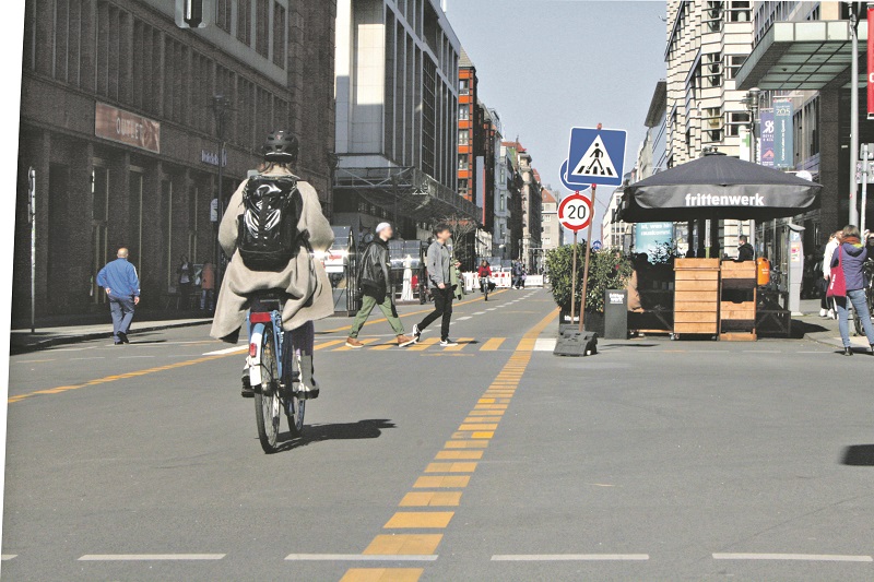 Fahrradfahrer und Fußgänger auf eienr Straße ohne Autos