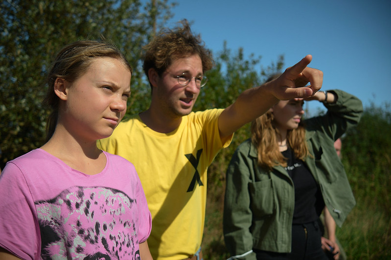 Zwei Frauen und ein Mann blicken in die Ferne. Der Mann im gelben T-Shirt zeigt auf etwas.